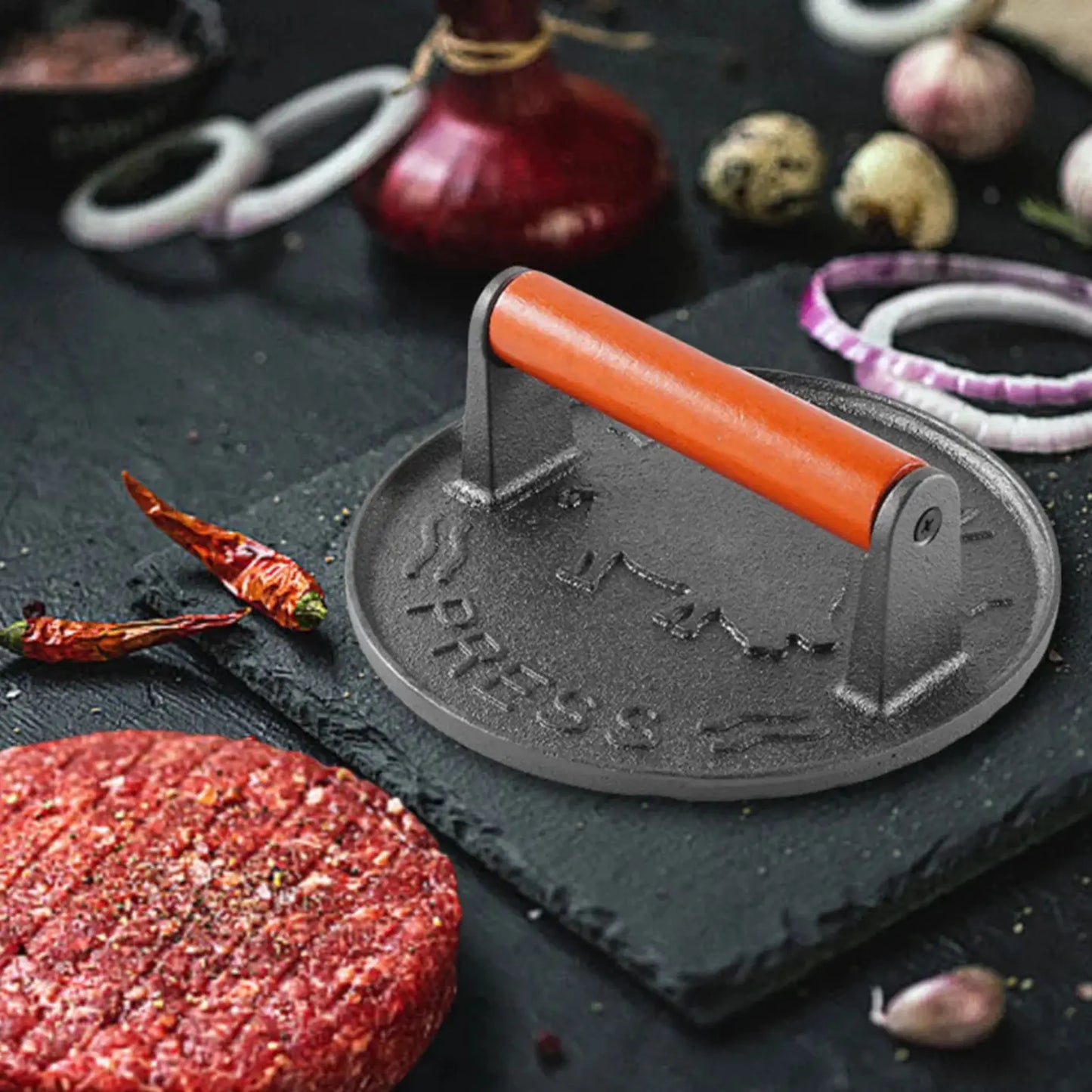 Hamburger press on a dark surface with ingredients.