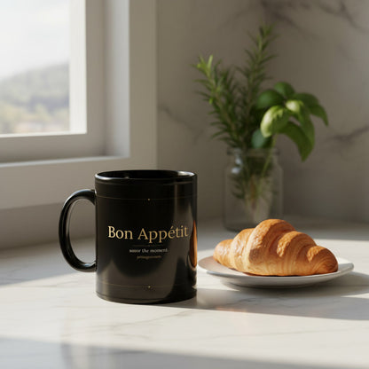 Bon Appetit black glossy mug on marble kitchen countertop with a croissant and fresh herbs in morning light - petitegourmets