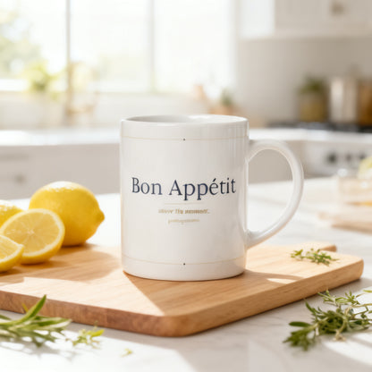 Bon Appetit white glossy mug on wooden cutting board with fresh lemons and herbs in bright airy kitchen - petitegourmets