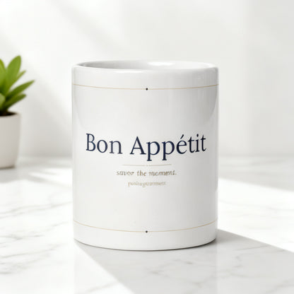 Bon Appetit white glossy mug on white marble surface with soft natural light and small green plant - petitegourmets