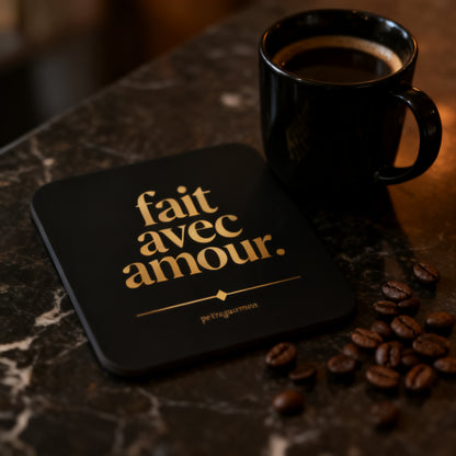 Fait Avec Amour black and gold coaster next to black coffee mug with scattered coffee beans on dark marble - petitegourmets
