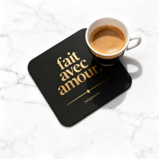 Fait Avec Amour black and gold cork-back coaster with espresso cup on white marble surface - petitegourmets
